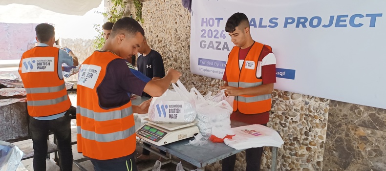 حديث عن الصدقه في رمضان متطوعون يرتدون سترات برتقالية يعبئون ويوزعون أكياس الطعام ضمن مشروع وجبات ساخنة إنساني.